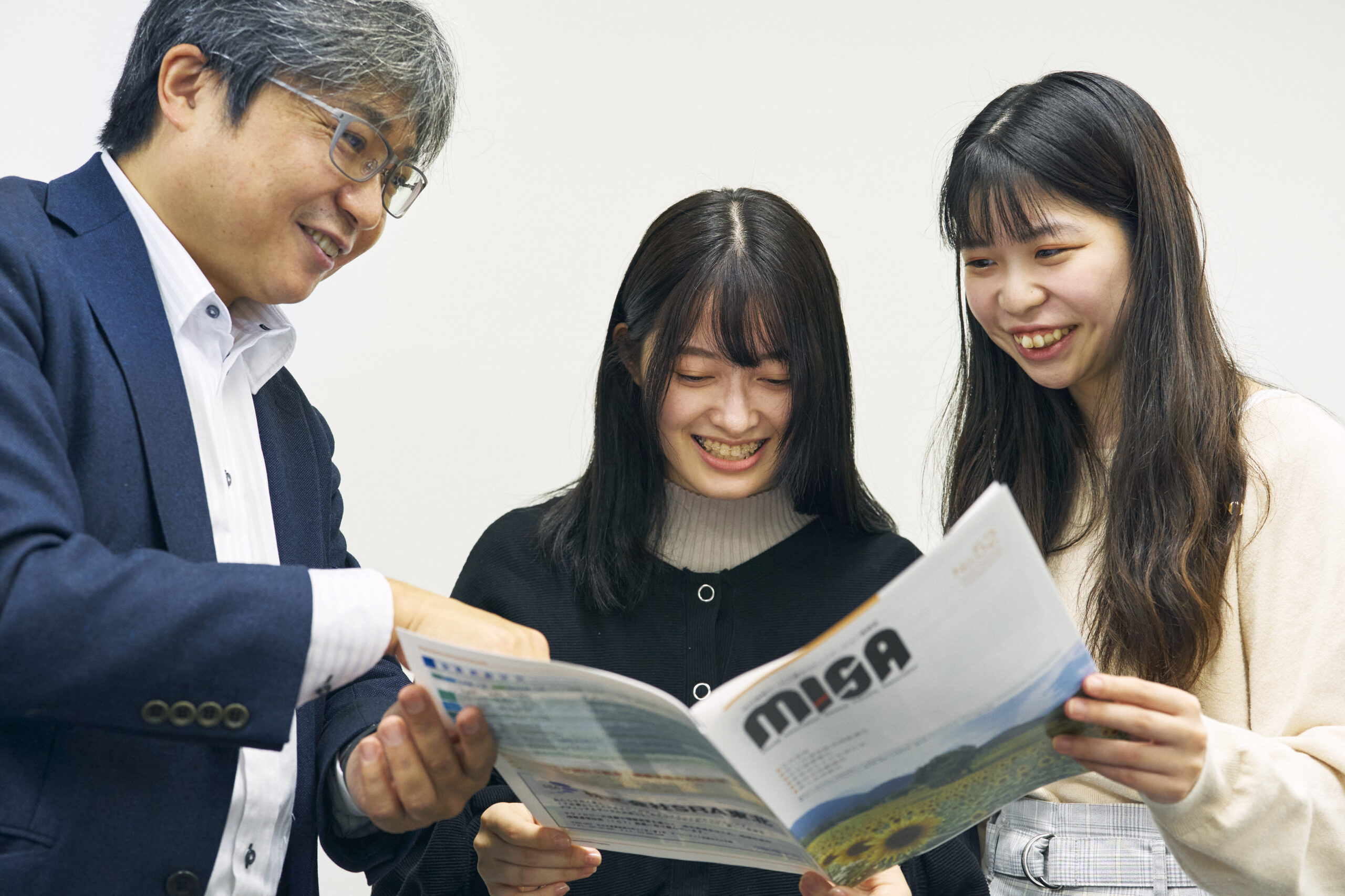 MISAの冊子を読む髙谷将宏さんと中村穂香さんと及川瑠莉さん